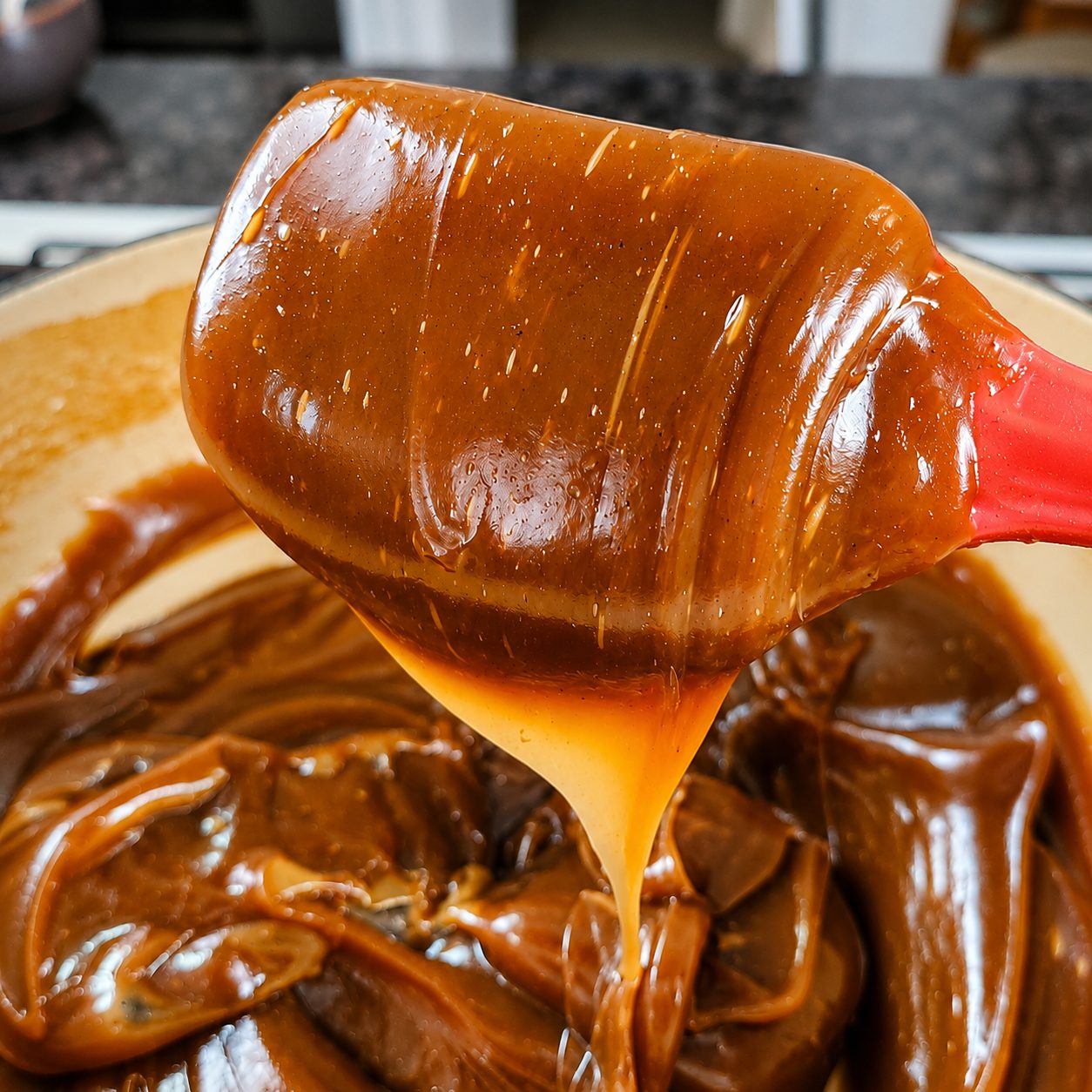 Dulce de leche cayendo de la espátula, brillo y textura de cerca